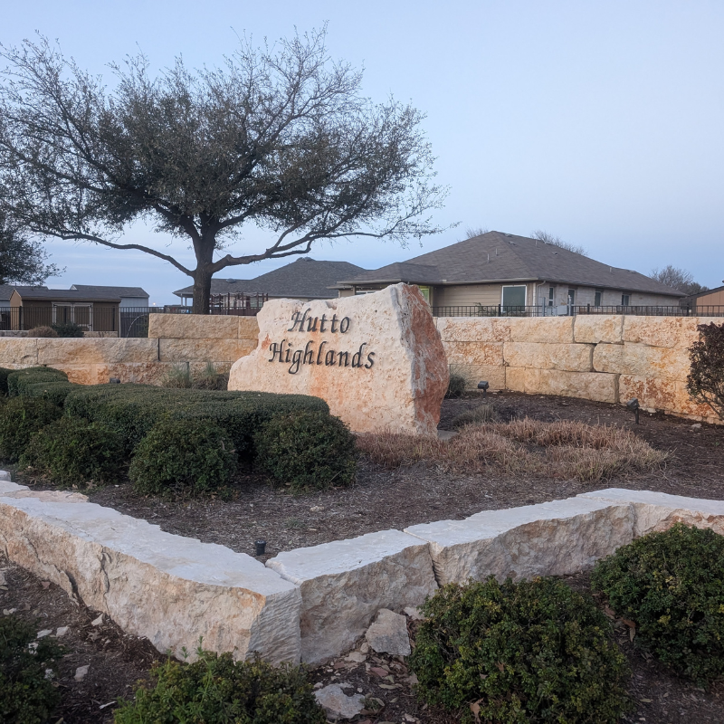 Stone entrance sign and landscaping cleaned with pressure washer by Luke's Pressure Washing