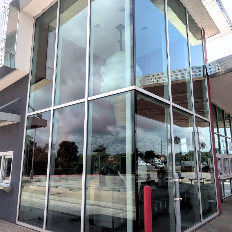 Modern commercial building with large floor-to-ceiling windows reflecting the sky and surrounding area, showcasing the type of exterior glass cleaning performed by Luke's Pressure Washing.