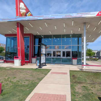Wide view of a drive-thru restaurant with clean windows and a well-maintained sidewalk after pressure washing service.